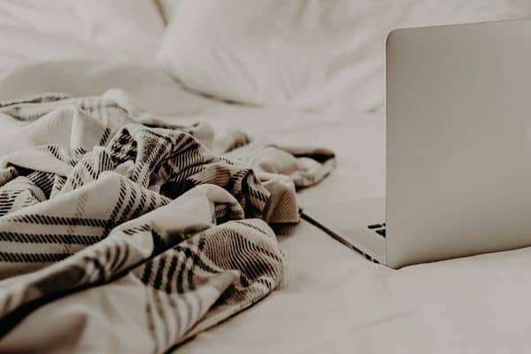 Laptop on the bed with a linen blanket on the bed
