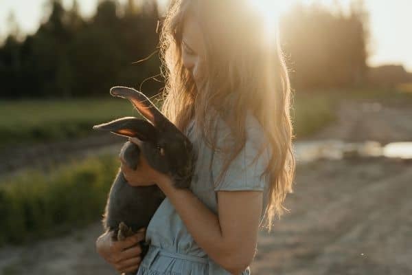 woman holding a rabbit learning how to raise meat rabbits