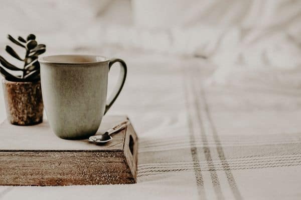 cup of coffee on a breakfast try sitting on a bed