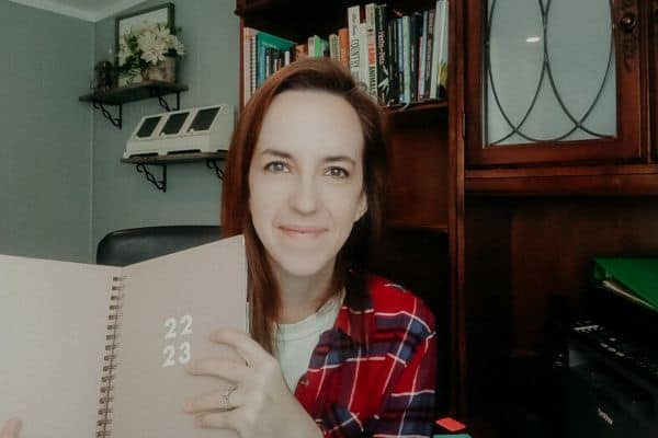 Leah lynch holding a planner in her home office.